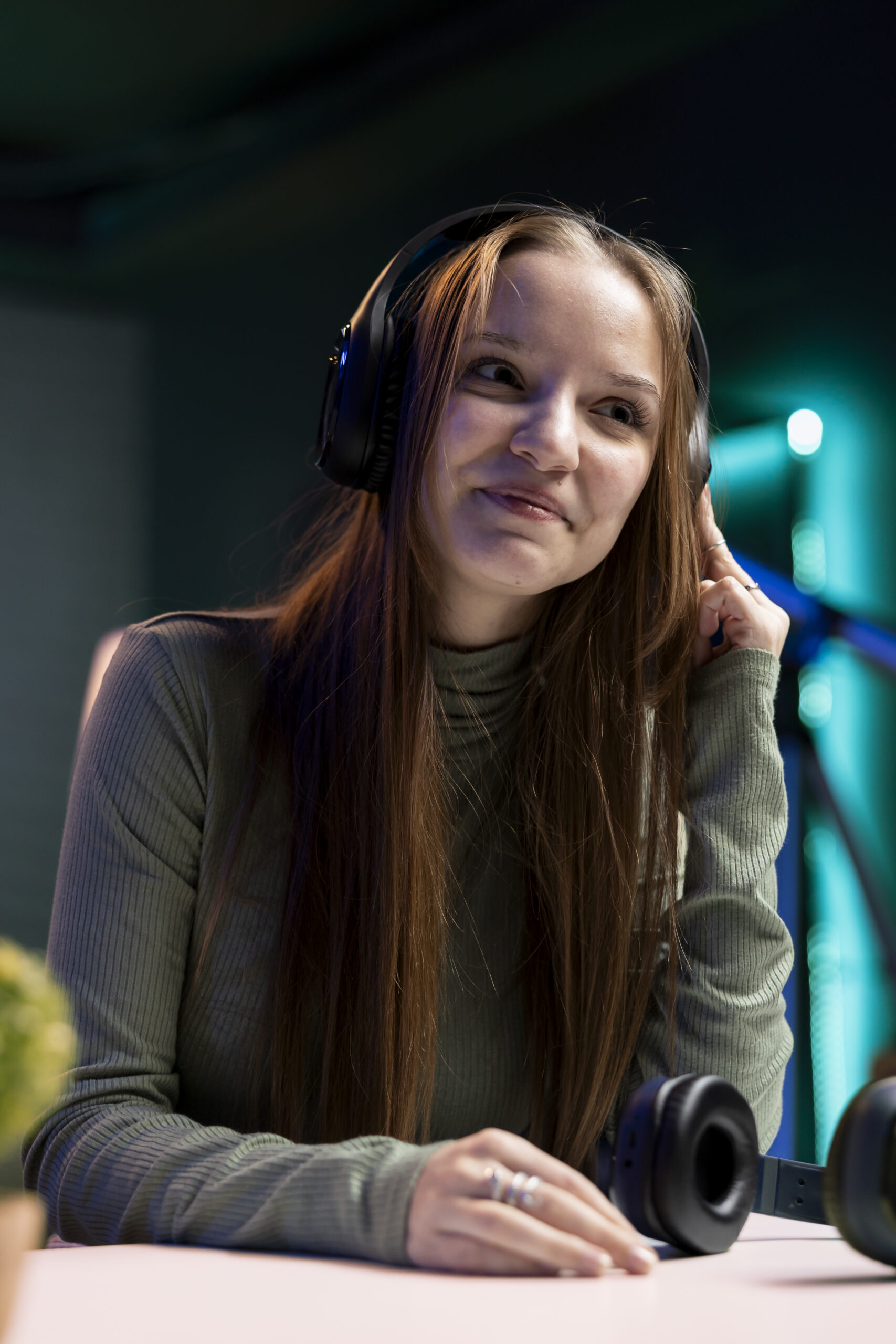 Smiling gen Z girl filming herself enjoying new album from favorite musician, reviewing music. Upbeat content creator hosts internet show, rating songs, hearing them through headphones