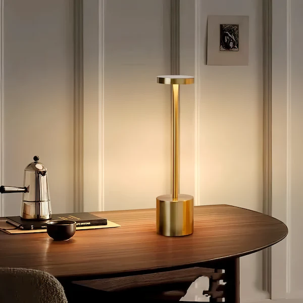 A gold Wireless Desk Lamp sits on a table in a luxurious setting.