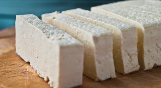 Firm pressed tofu slices on cutting board, perfect texture for recipes using Tofuture tofu press and tofu press coupon code.